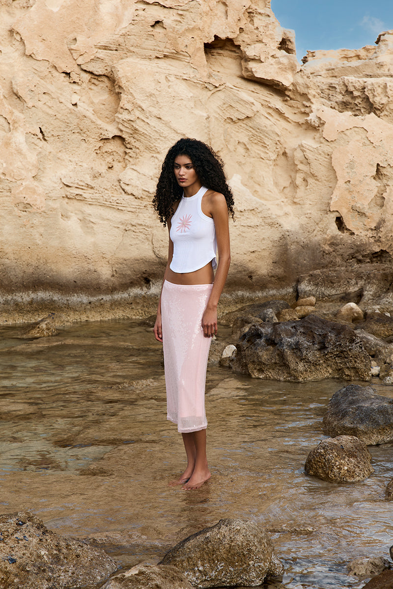 Light pink IKINITA Sunrise Top with ruffled neckline and short sleeves, displayed on a hanger.