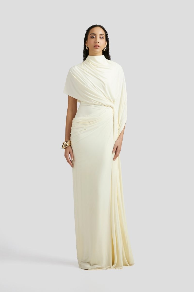 Deme By Gabriella Luciana maxi dress in off-white with flowing fabric and elegant design displayed in the image.
