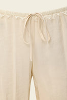 Cream Scylla pants by IKINITA, featuring a relaxed fit and stylish design, displayed on a model in a casual setting.