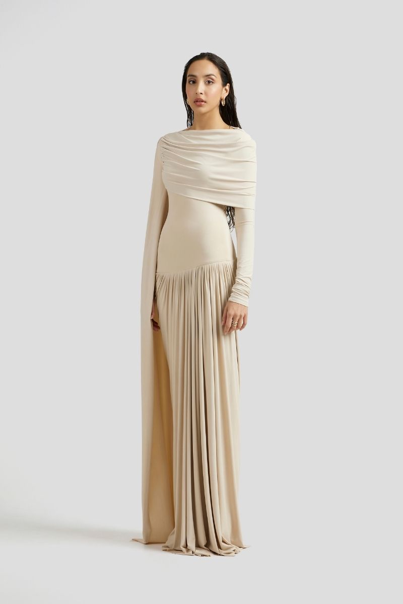 Deme By Gabriella Amara maxi dress in ivory, flowing fabric with elegant design and sleeveless style, displayed on a hanger.