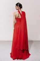 Red pleated gown with cape by HACCHIC COUTURE, elegant evening dress featuring flowing fabric and stylish cape detail.