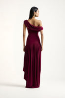 Deme By Gabriella Cassidy maxi dress in aubergine with flowing fabric and elegant design, displayed hanging on a mannequin.
