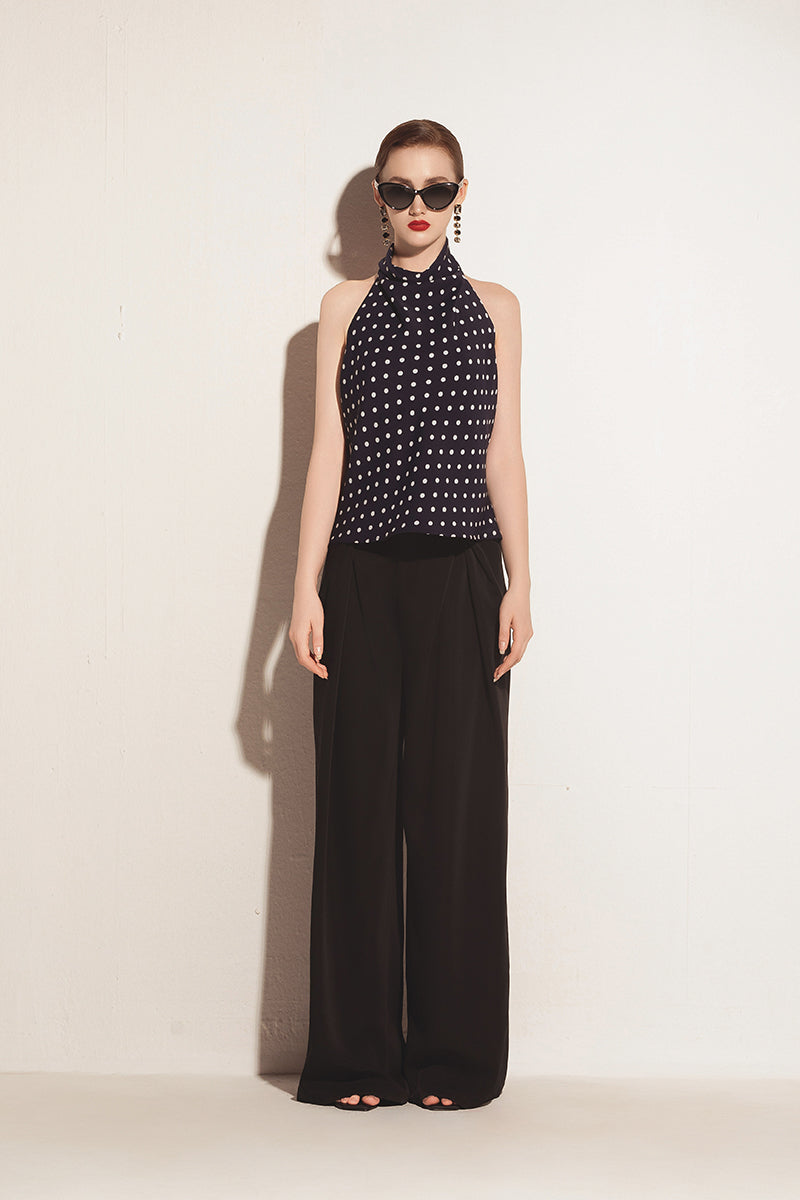 Black Valenciani halter neck backless top, shown on a model, featuring a stylish backless design and sleek halter neckline.