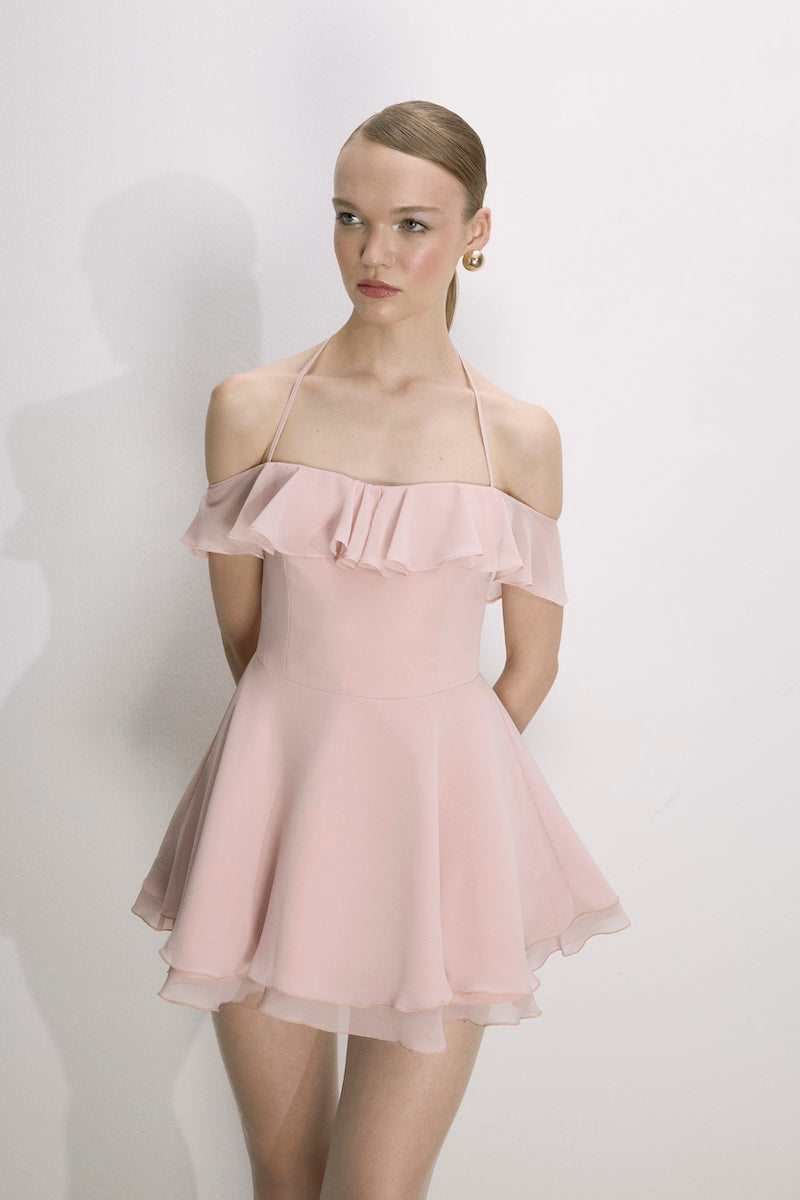 Nazlı Ceren Evie mini dress in tender peach, sleeveless with a fitted silhouette, displayed on a hanger against a neutral background.