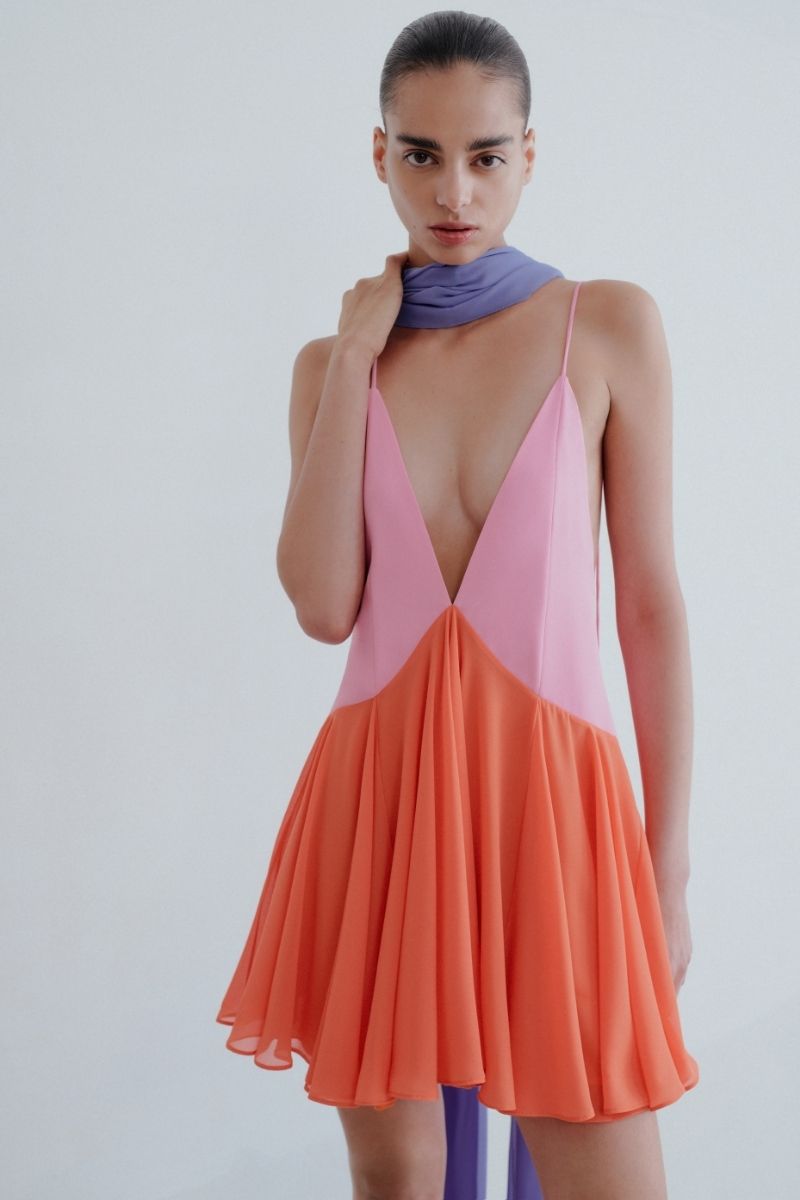 Sisters Kimberly mini dress in peachy pink, sleeveless with a fitted silhouette and ruffle details, displayed on a hanger.