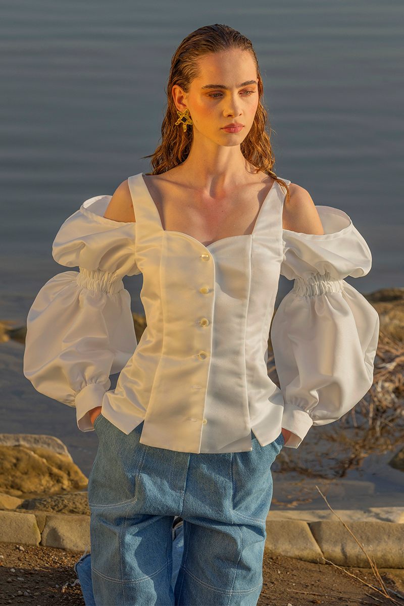 Liya ruffle sleeves shirt in soft fabric with feminine ruffle detailing on the sleeves, styled as a trendy casual top.