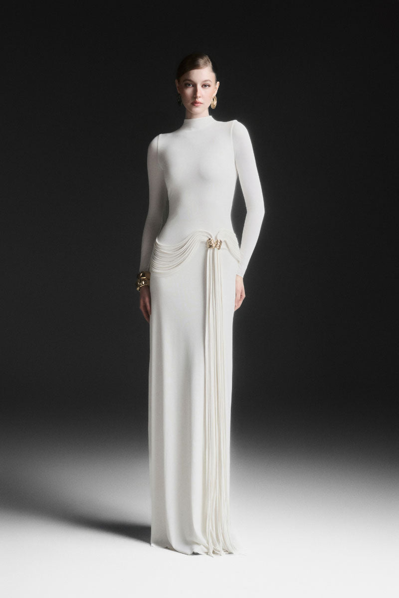 Maison Des Copains white Corvina draped floor-length gown shown on a model, featuring elegant flowing fabric and sophisticated style.