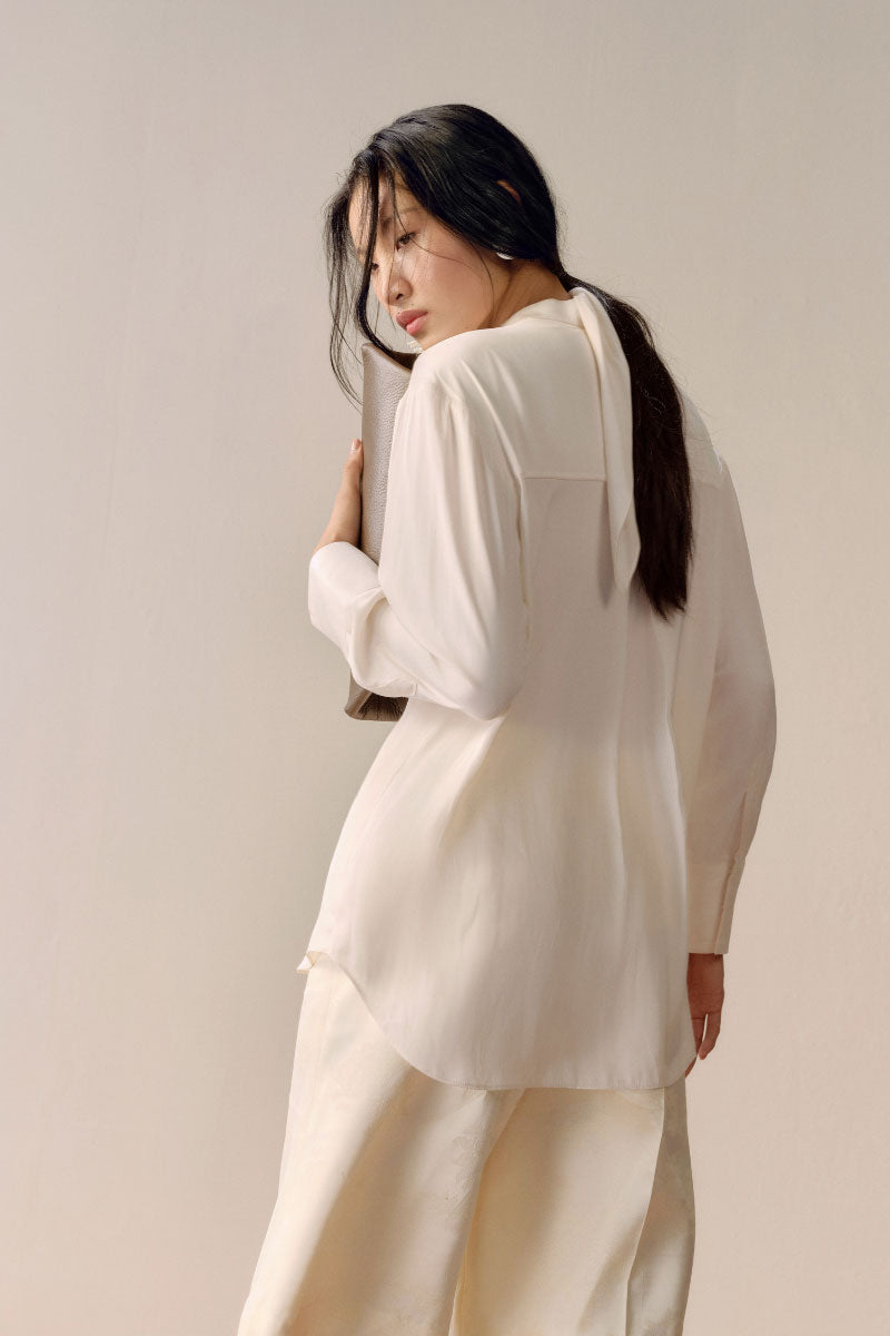 Ivory satin twilly shirt by LECIA featuring smooth, shiny fabric and a stylish neckline, displayed on a hanger.