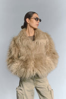 Beige fluffy faux fur jacket by Fortini, stylish and cozy, shown on a model with a high collar and textured soft fur exterior.