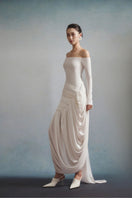 White Plan AURÉLIA draped maxi dress with flowing fabric and elegant design, shown on a model with soft lighting.