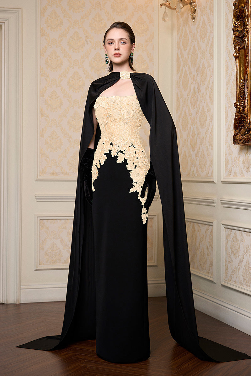 Beige strapless column gown with long cape by I.H.F, shown on a mannequin highlighting elegant, flowing fabric and sophisticated design.