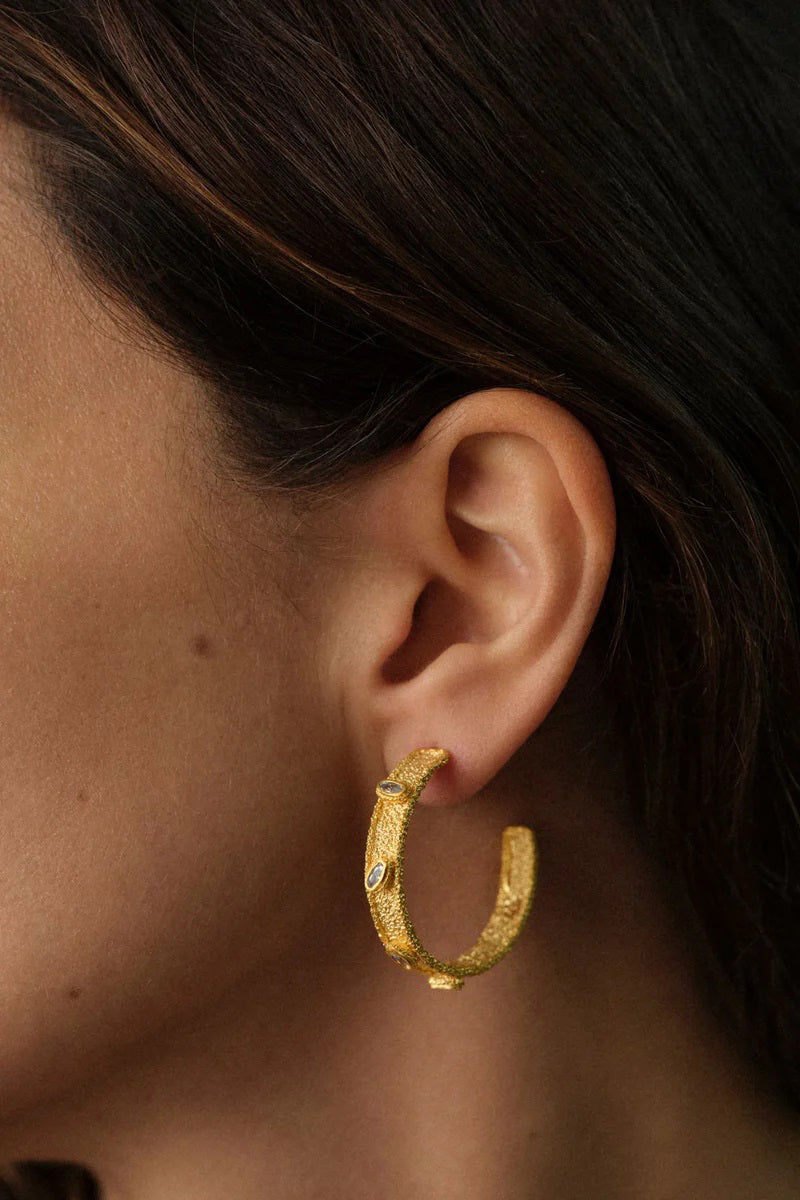 PERACAS Salma hoops earrings in white, stylish and minimalist jewelry with round hoop design, close-up view of the white earrings.