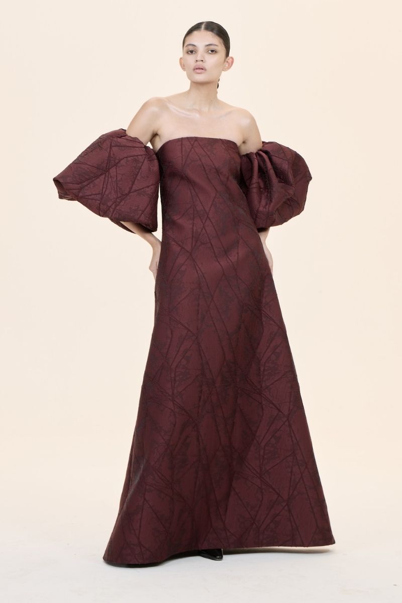Nihan Peker Mustesna gown featuring elegant fabric and detailed craftsmanship, displayed on a hanger against a neutral background.