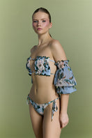 Nur Karaata Misty Mirage bikini showing a colorful, patterned two-piece swimsuit on a model against a beach backdrop.