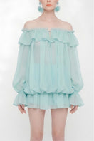 Turquoise Valenciani off-shoulder mini dress styled as a scarf, featuring vibrant fabric and fashionable draping.