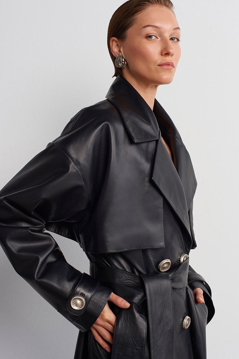 Black leather trench jacket by Acaria Studio, stylish and sleek, shown from the front with classic lapels and belt detail.