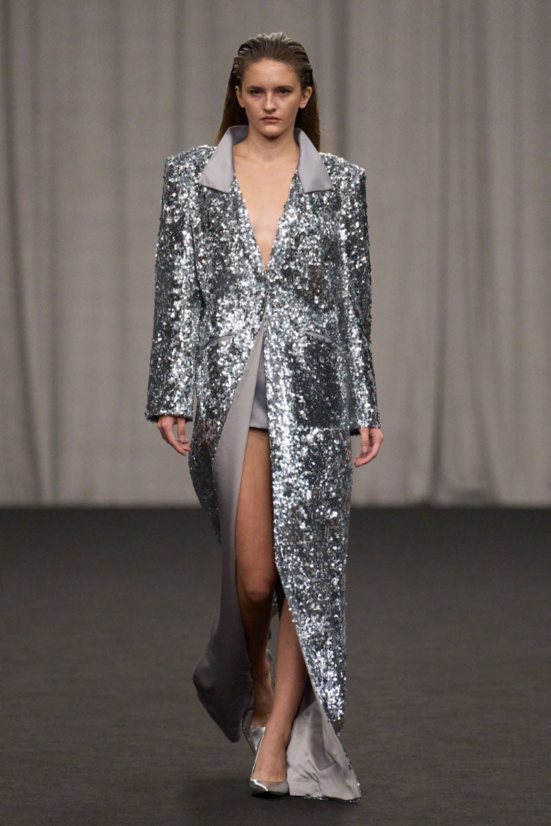 Lili Blanc sequin longline coat with shimmering fabric, tailored fit, and classic collar, perfect for elegant winter wear.