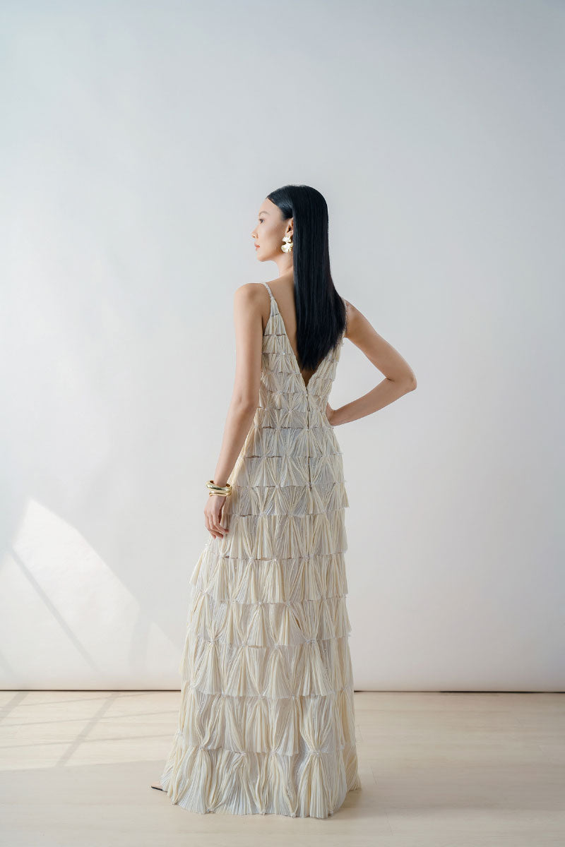 Beige deep V-neck tiered pleated maxi dress by DOC BAN displayed on a model, featuring flowing fabric and elegant design.