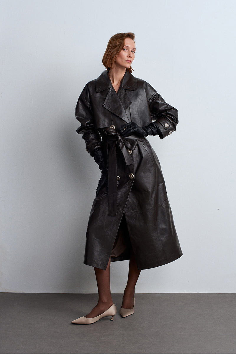 Dark brown leather trench coat by Acaria Studio, featuring classic design and tailored fit, displayed on a hanger.