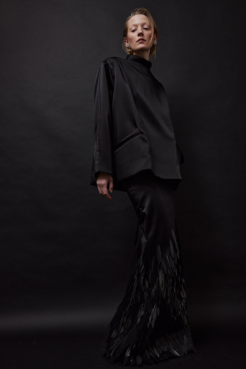 Black satin oversized blouse from TAGG, featuring a loose fit and smooth satin fabric, displayed on a hanger.