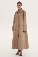 Beige rose embroidered trench coat by DELEGAN, showing detailed floral embroidery and classic coat design.