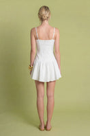 White sunny dress by Laura Escobar, mini dress style with a flowy fabric and stylish design, shown on a model.