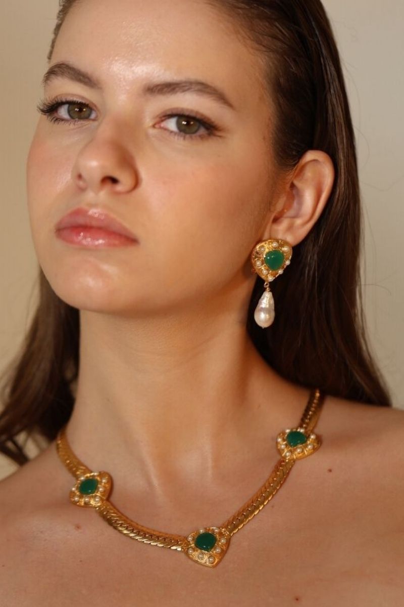 Gold Claudia Necklace by ANATINA featuring a delicate chain and elegant pendant, styled on a neutral background.