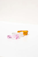 Set of three SALVÁREA rings in pink, amber, and white remolino design, featuring stylish and colorful band details.