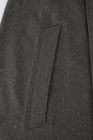 Brown long wool cape coat by JINSUN displayed on a hanger, showcasing its elegant, flowing fabric and classic design.