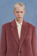 Pink oversized Suri alpaca coat by JINSUN, featuring a soft, plush texture and relaxed fit, displayed on a hanger.