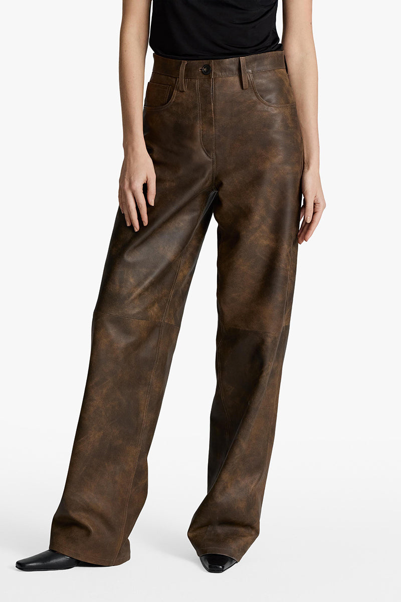 Acaria Studio root washed leather pants showing a close-up of soft, textured, dark leather fabric and tailored fit.