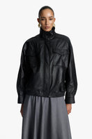 Acaria Studio Zoe leather bomber jacket displayed on a hanger, featuring a sleek black design with ribbed cuffs and collar.