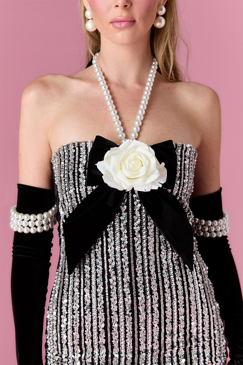 Nur Karaata Vivienne Rose mini dress, sleeveless with floral print, fitted waist and ruffled hem, on a model.