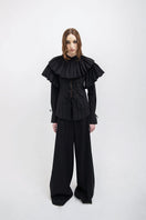 Black Vaska shirt featuring a large collar, long sleeves, and a relaxed fit, displayed on a hanger.