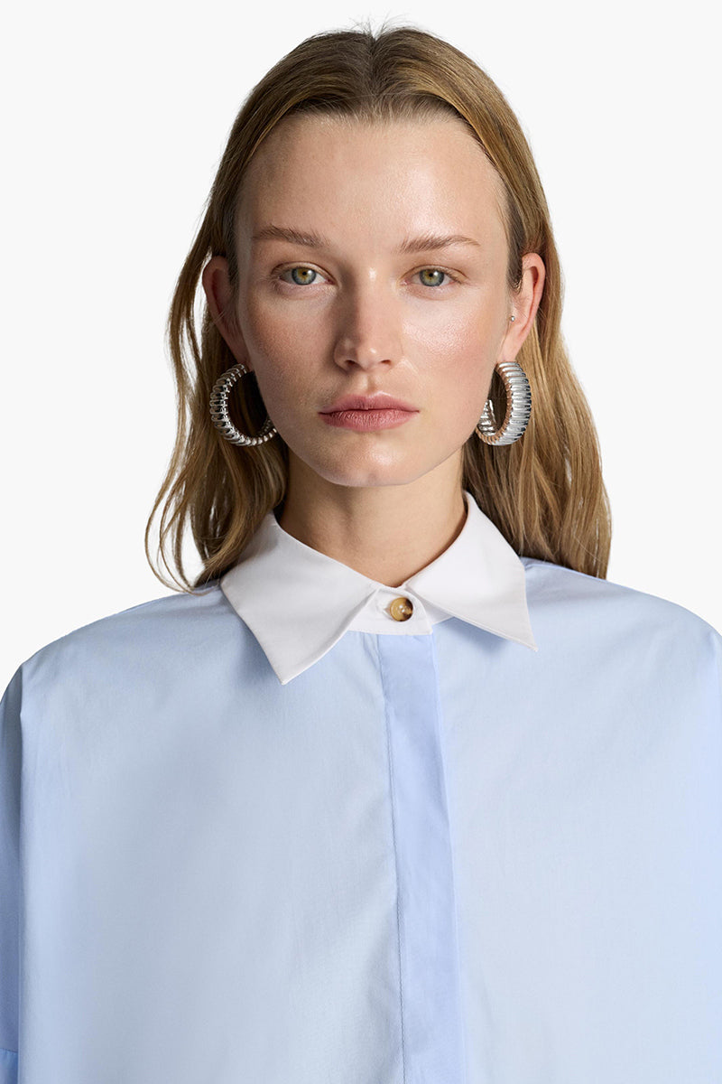 Acaria Studio iconic French blue shirt with long sleeves and classic collar, displayed on a hanger.