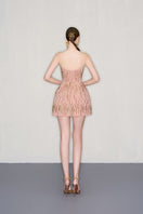 Blush-toned strapless mini dress by CEM with embellishments, fitted bodice, and flared skirt, displayed on a hanger.