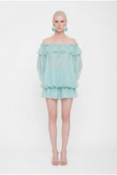 Turquoise Valenciani off-shoulder mini dress styled as a scarf, with flowing fabric and vibrant color.