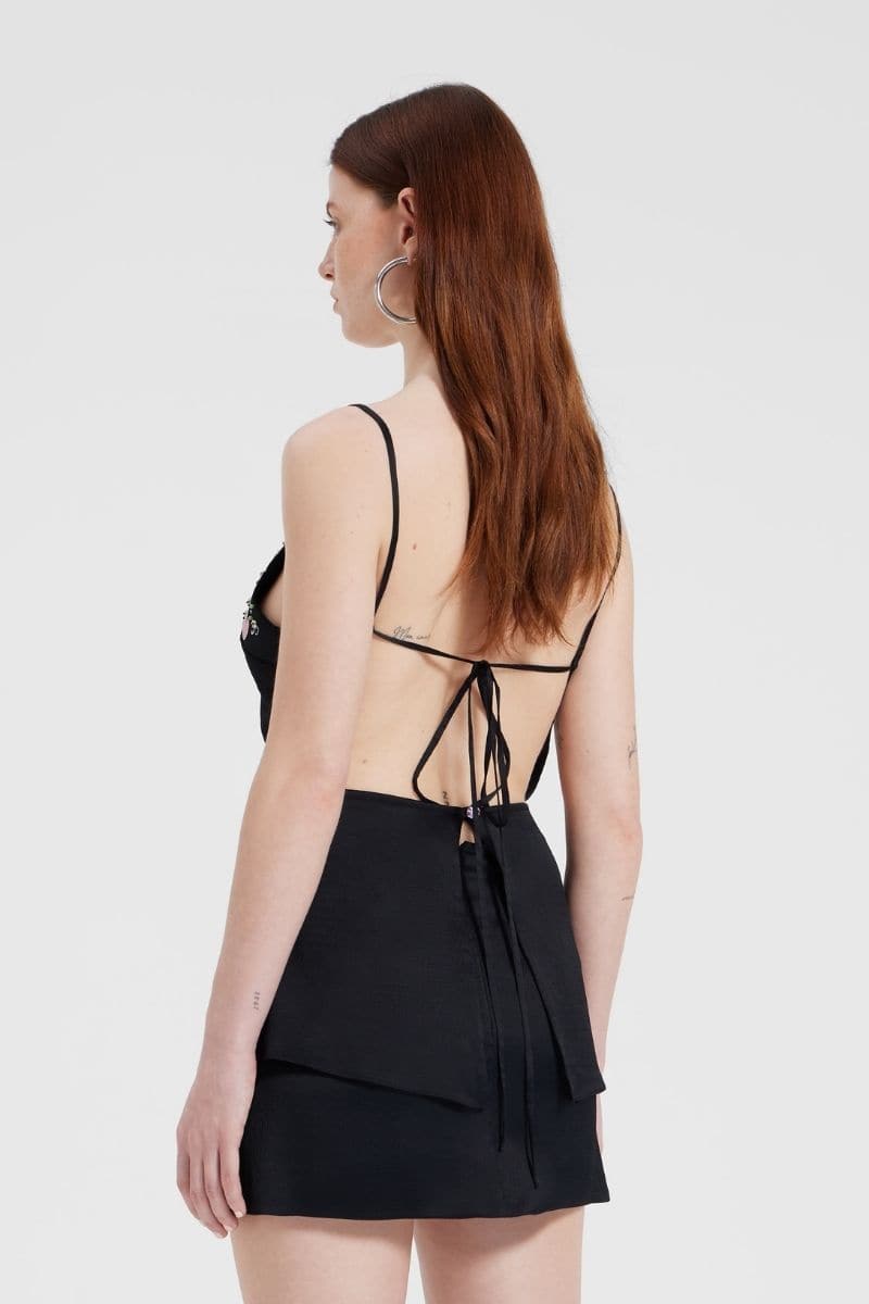 Black embroidered V-neck top by Nara Niro, featuring intricate embroidery and a stylish V-neck design, displayed on a hanger.