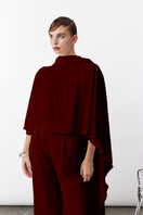 Nazlı Ceren Caro Crepe Cape in Bordeaux, stylish jacket with a flowing design, displayed on a hanger.