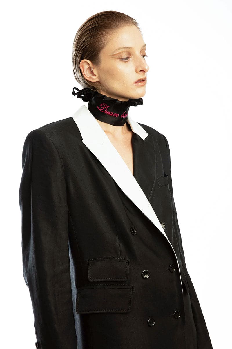 Vaska black double-breasted coat with white collar, tailored and stylish, displayed on a hanger.