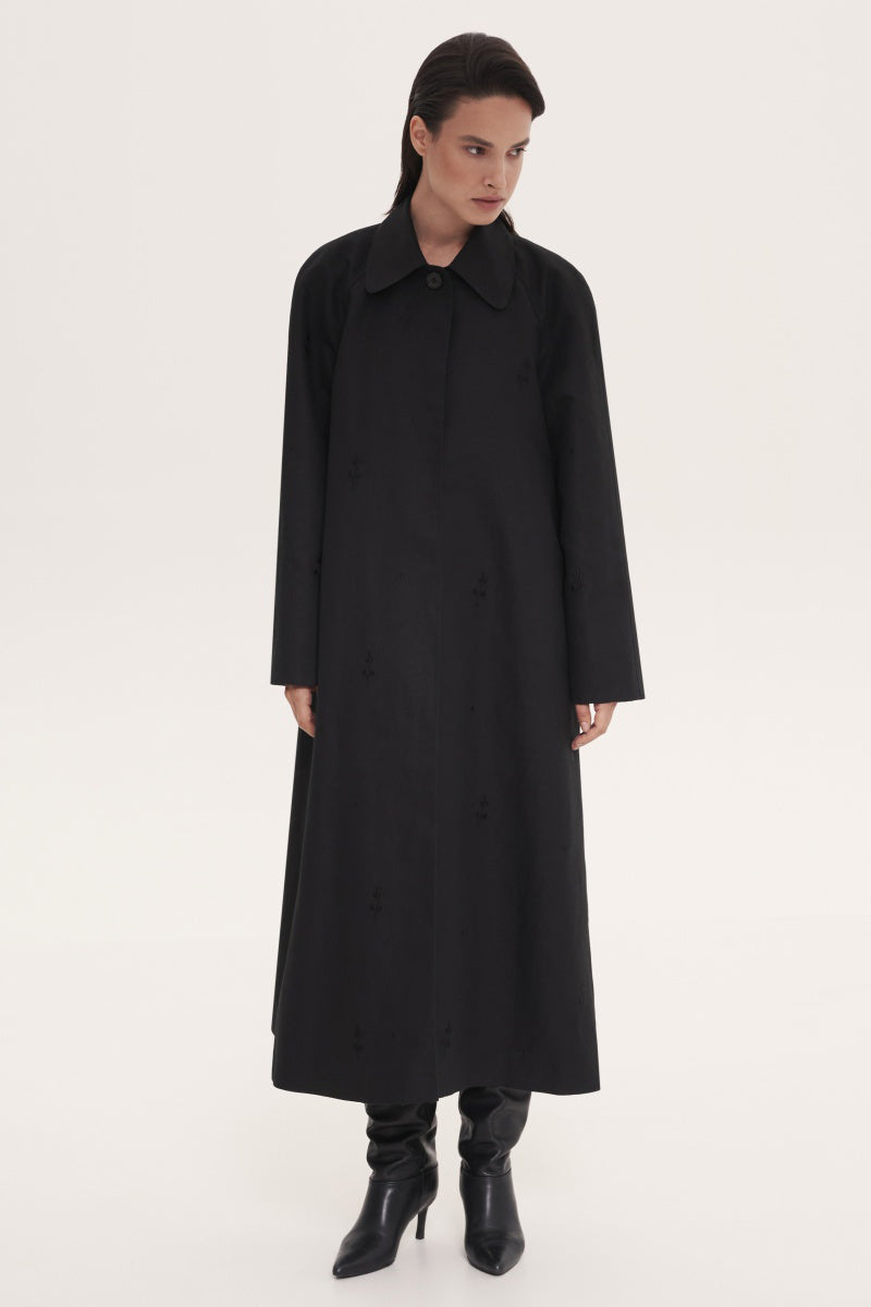 Black trench coat by Delegan, stylish long coat with classic design and button details, ideal for versatile outerwear.