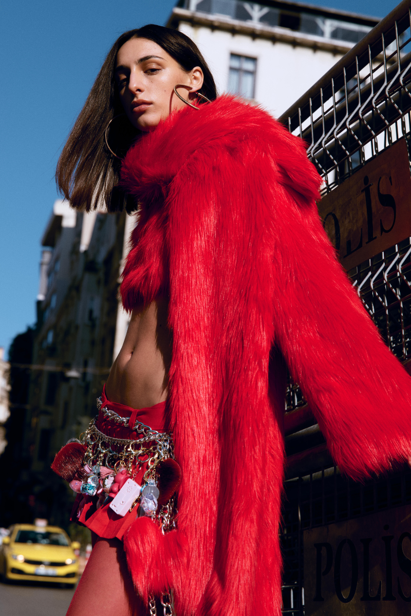 Sudi Etuz cropped faux fur coat with scarf detail, featuring plush texture and stylish design, shown on a model.