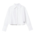 Dāl the Label cropped cotton button-down shirt with long sleeves and a classic collar, shown in a natural fabric texture.