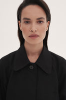 Black trench coat by DELEGAN featuring classic double-breasted design and tailored fit, shown on a model.