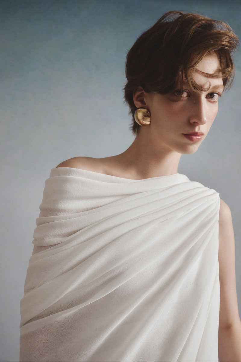 White Plan Lyra draped mini dress displayed on a hanger, showcasing its elegant, flowing fabric and stylish design.