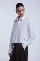 Dāl the Label cropped cotton button-down shirt in a casual style, featuring a classic collar and long sleeves.