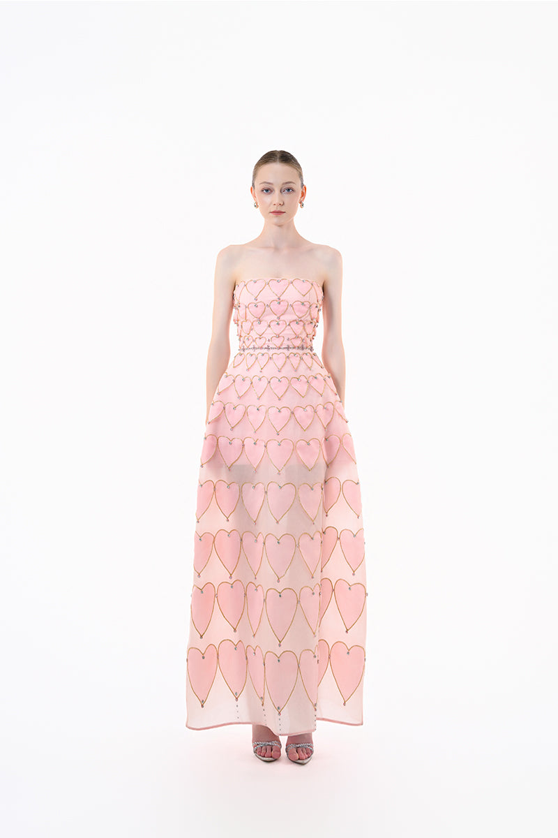 Blush pink embellished gown with heart motif by Happy Clothing, featuring intricate beadwork and flowing fabric.