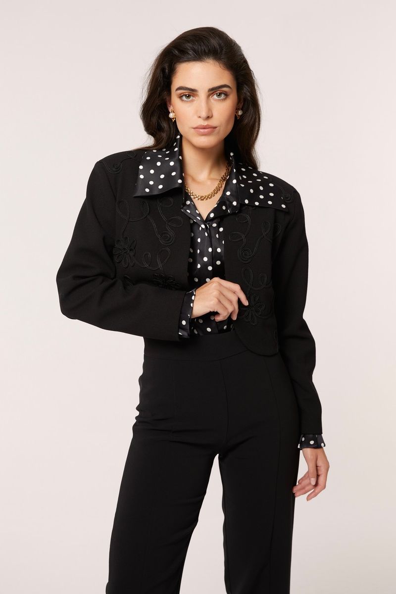 Black and white polka dot Señorita Antonia blouse with long sleeves and a relaxed fit, displayed on a hanger.