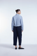 Dāl the Label cropped cotton button-down shirt in soft white, short sleeves, and relaxed fit displayed on a hanger.
