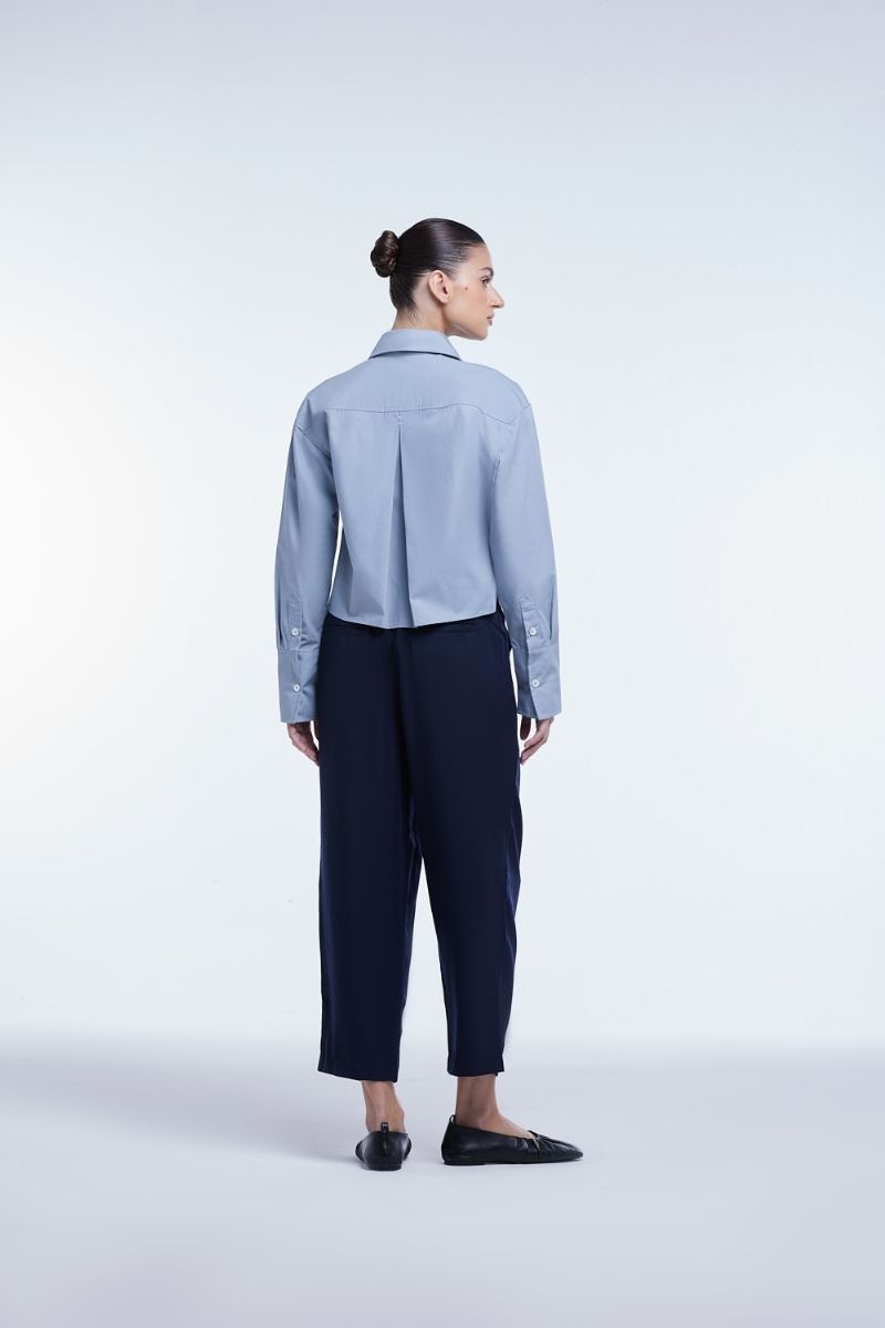 Dāl the Label cropped cotton button-down shirt in soft white, short sleeves, and relaxed fit displayed on a hanger.